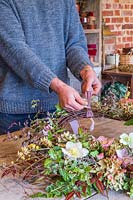 Man attaching pink ribbon to a rustic wreath