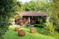 View across lawn with woven willow spheres to crafter' studio