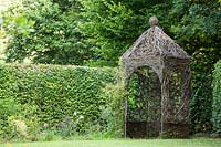 Gazebo, handcrafted with woven Salix - Willow, by a hedge 