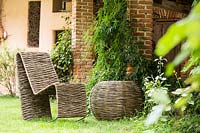 Handcrafted woven Salix - Willow - rocking chair and circular table on grass by building 