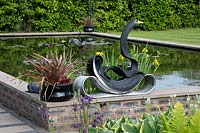Swan sculpture made from an old tyre, on the edge of a raised pond 