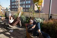 Guests relax in hammocks on the hostel's terrace, surrounded by Mediterranean plants. 