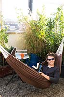Guest relaxes in hammock on the hostel's terrace, surrounded by Mediterranean plants. 