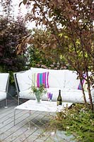 Decked terrace with corner relaxing area screened by container grown shrubs