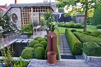 Contemporary garden with pond, water feature and box topiary.