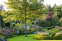 View across garden, with mown lawn and summer herbaceous borders.