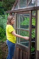 Opening a greenhouse door for ventilation in summer. 