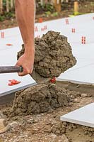 Man with shovel of mixed cement for a patio base