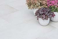 Pots of colourful plants sat upon clean context porcelain patio