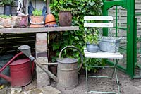 Rustic wooden seat, old watering cans and homemade potting table
