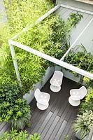 Looking down on metal pergola over office terrace garden with chairs and container planting