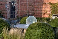 Aqualens water feature designed by Allison Armour with large clipped balls of Buxus sempervirens and Stipa tenuissima grass. 