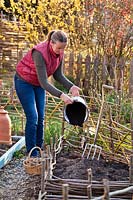 Woman adding compost to a vegetable bed