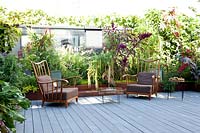 Relaxed seating area beside a border wall created to hide the adjacent building, mirrors give the illusion 
Â the terrace is larger. Corten containers planted with chard, pennisetum, amaranths and castors in variety, rosemary, tulbaghie