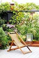 Relaxed seating area beside a border wall created to hide the adjacent building. Corten containers planted with chard, pennisetum, amaranths and castors, rosemary, tulbaghie