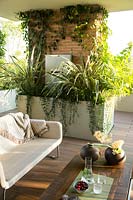 View over the living area to brick pillar with trough with mixed planting of Phormium and other foliage plants 