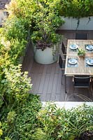 Looking down corner of a decked roof terrace with the foliage screen around dining area