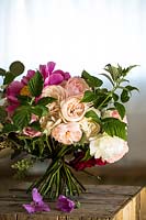 Handtied bunch of Rosa - Rose - and Paeonia - Peony - on wood