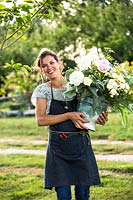 Woman wearing work apron after picking a bucketful of cut flowers from the fields