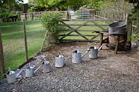 Watering cans arranged in height order near old water tank 