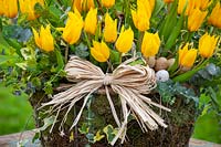 Basket of yellow tulips, pussy willow and ivy with raffia and eggs