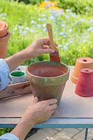 Woman painting terracotta pot green