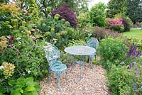 Table and chairs on gravel seating area surrounded by mixed borders 