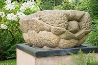 Stone turtle sculpture on a plinth set in a garden