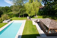 Modern tiered garden with swimming pool and summer house, set in lawn with hard landscaped details