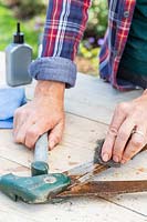 Woman using wire wool and oil to clean a pair of lawn edging sheers