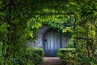 Gate as seen through green tunnel at Boughton Monchelsea Place, Kent, UK. 