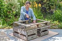 Woman attaching wooden battons to pallet base to strengthen design