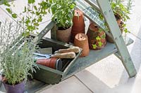 Detail of wooden shelving ladder unit with potted plants and tools
