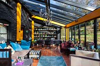 View inside conservatory with black and yellow painted walls. seating area overlooking garden. 
