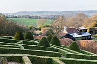 Sloping formal country garden with views of countryside beyond. April. 