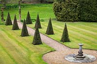 Overview of formal lawn with Taxus baccata pyramids lined path and central sundial
