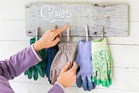 Woman attaching pair of gloves to storage board. 