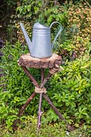 Watering can sitting on tripod table