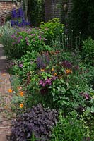 View over perennial flowering border in walled garden.