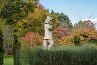 Statue of muffled man against a blackdrop of deciduous trees and shrubs