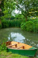 Dinghy moored on garden pond with distant marginal plants - Open Gardens Day, Earl Stonham, Suffolk