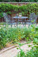 View across suburban garden towards black metal dining table and chairs