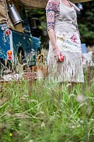 Woman wearing floral and linnen apron with landrover in background