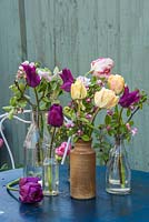 Purple and yellow tulips displayed with apple blossom in glass and pottery bottles
