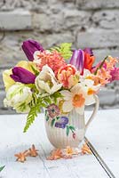 Mixed spring bouquet in vintage jug with tulips, hyacinths, ferns and narcissus
