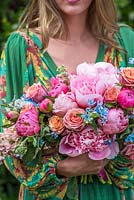 Girl holding boho wedding style bouquet with peonies and roses
