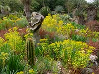 Dry garden with mixed planting among rocks and sculpture 