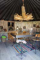 Interior of hut with cantilevered table, chairs and pizza oven