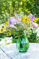 Vase with Rudbeckia, Aster, Anemone and grasses on garden table in September