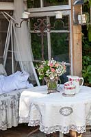 Coffee table with vintage crockery in garden room with swing chair